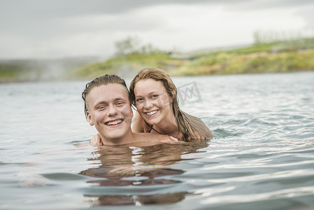 微笑的年轻夫妇在冰岛福夫迪尔的秘密泻湖温泉放松