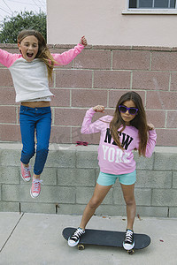 少女肌肌摄影照片_两个女孩在玩一个在玩滑板