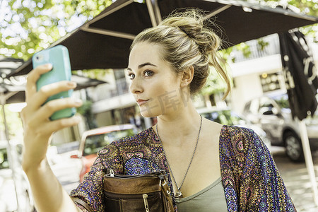 在南非的路边咖啡馆一名年轻女子在智能手机上查看自己
