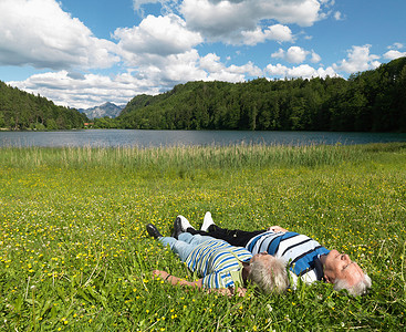 老夫妇躺在湖边的田野里