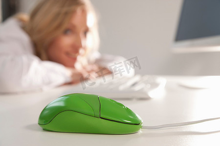 办公室桌面上的绿色鼠标与女性
