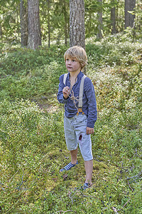 看电视的小男孩摄影照片_站在森林里穿着复古服装的小男孩的肖像