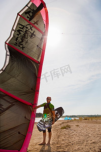 风筝冲浪者在阳光明媚的日子里拿着风筝和冲浪板