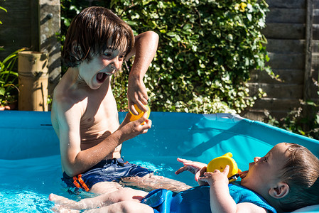 夏日快乐的兄弟在充气泳池里玩耍