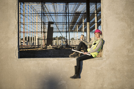 vis设计摄影照片_坐在建筑工地窗框上的女建筑师