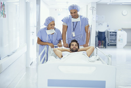 年轻男性患者在医院病床上被护士推着