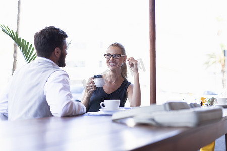 成熟的男人和女人坐在咖啡馆外喝着咖啡面对面微笑着