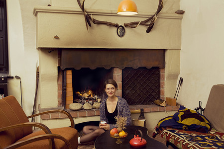 三鲜豆腐摄影照片_坐在壁炉旁地板上的年轻女子的肖像