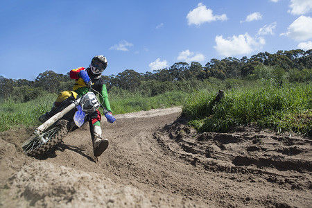 年轻男子越野摩托车手在泥泞的赛道弯道上赛车