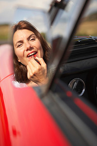一名女子在汽车镜子上涂口红