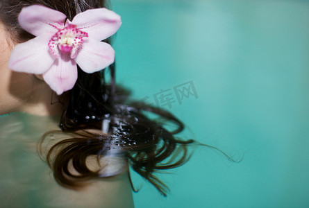 剪下的女人在温泉游泳池里的照片头发上有紫色的兰花