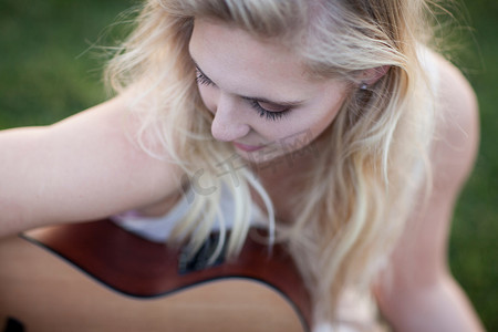 在草地上弹吉他的女人