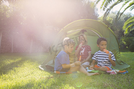 三个孩子在花园帐篷里吃冰棍
