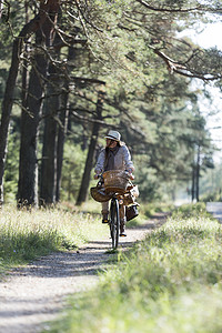 带着觅食篮子在森林小路上骑自行车的妇女