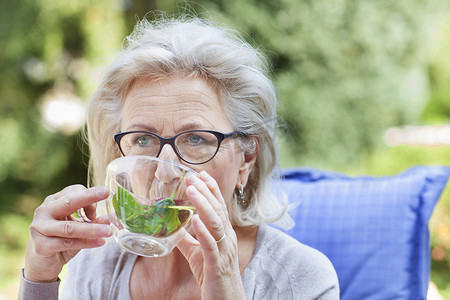 老年妇女在花园里放松喝着饮料