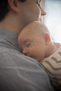 童装上新摄影照片_睡在父亲肩膀上的男婴近距离观察
