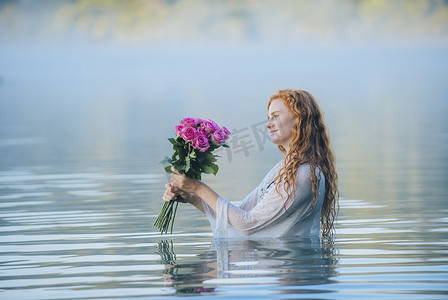玫瑰家族摄影照片_站在湖边的年轻女子凝视着一束粉色的玫瑰