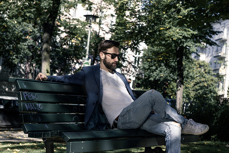 盘腿坐着摄影照片_一名男子坐在公园长椅上柏林德国