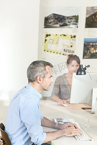 透过玻璃观看用电脑侧视办公室里的成熟男人
