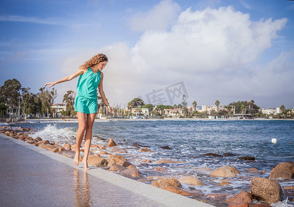 民族大道摄影照片_一名年轻女子赤脚走在海滨大道上