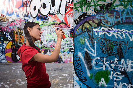 气雾罐摄影照片_一名年轻女子在喷洒涂鸦