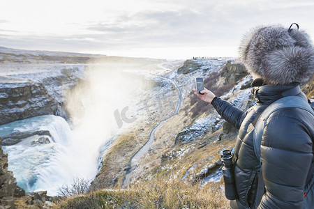 拍摄位于冰岛西南部河峡谷的瀑布的女子