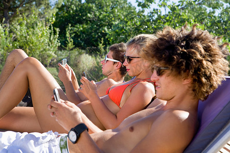 青少年集体查看躺在阳光下的手机
