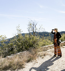 动物望远镜摄影照片_用双筒望远镜望向别处的观景台上年轻女子的全景美国洛杉矶加利福尼亚州奇劳露营地