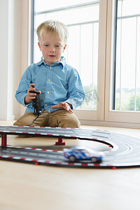 男孩在客厅地板上玩玩具赛车