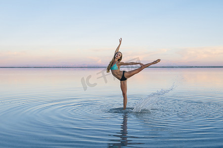 美国犹他州波纳维尔盐滩湖上一条腿站立的女芭蕾舞演员
