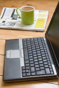 一台笔记本电脑一个杯子和一份报纸