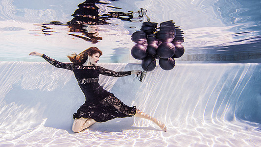 一名女子在游泳池里穿着裙子手里拿着一堆气球
