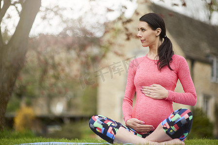 幼儿拉肚子摄影照片_孕妇坐在户外抱着肚子