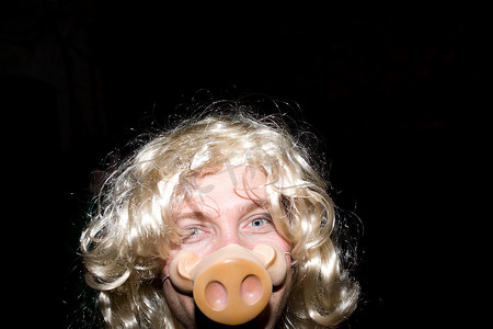 猪鼻子摄影照片_戴着金色假发和猪鼻子面具的男人
