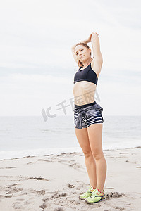 中年女性运动摄影照片_中年成年人在海滩上伸展的肖像
