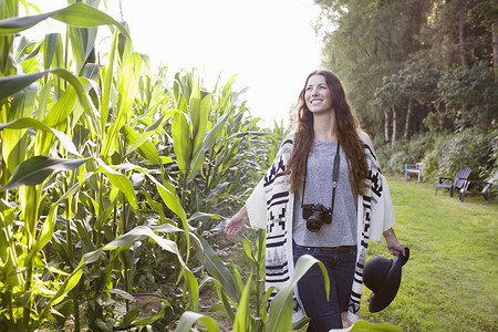 年轻女摄影师在田野里漫步触摸玉米植株