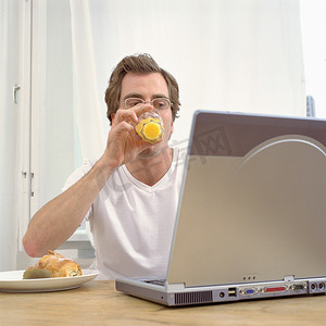 早餐时拿着笔记本电脑的男人