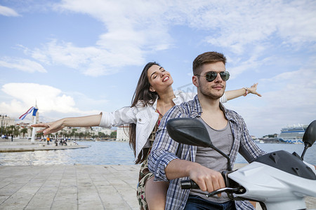 生活方摄影照片_克罗地亚达尔马提亚年轻夫妇在港口骑着轻便摩托车斯普利特