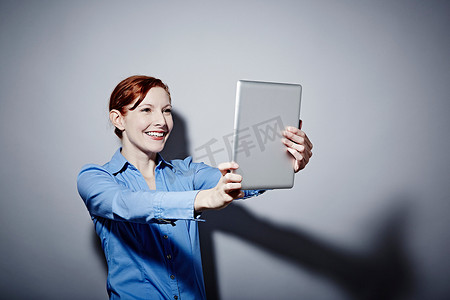 工作室年轻女子举着数字平板电脑的肖像