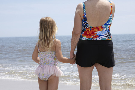 上手图摄影照片_老妇人和孙女在海滩上手牵手的背影