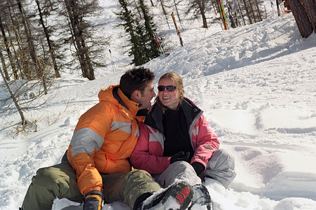 坐在雪地里摄影照片_一对夫妇坐在雪地里笑着