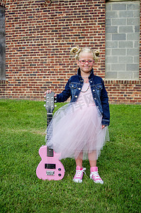 牛仔夹克摄影照片_年轻女孩穿着芭蕾舞裙和牛仔夹克拿着吉他