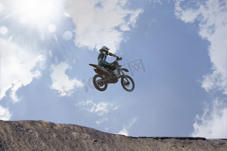 山摄影照片_轮廓分明的年轻男子越野摩托车手跳过泥山