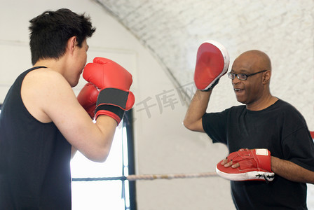 防护鞋摄影照片_拳击手在健身房和教练一起训练