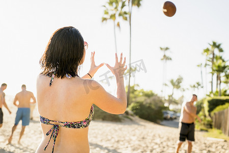 一群人踢足球摄影照片_在美国加利福尼亚州纽波特海滩上踢美式足球的成年朋友