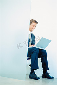 上卫生间摄影照片_坐在马桶上拿着笔记本电脑的商人