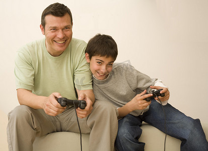 男孩和父亲在沙发上玩电子游戏控制器