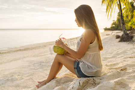 菲律宾博霍省安达海滩上喝椰子汁的年轻女子
