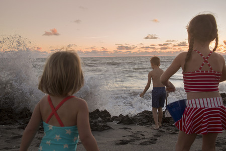 男孩和姐妹们在日出时看着溅起的海浪吹石保护区美国佛罗里达州朱庇特岛