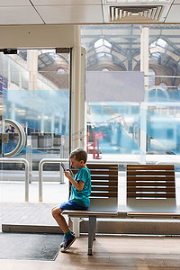 小男孩在火车站候车室玩电子游戏